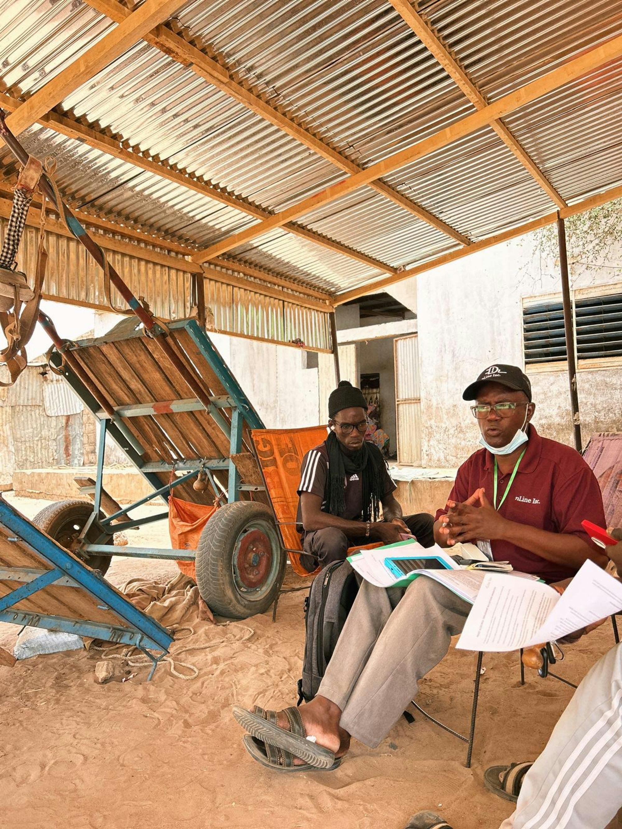 A community guide looks on as the surveyor carries out a brief survey with a household.