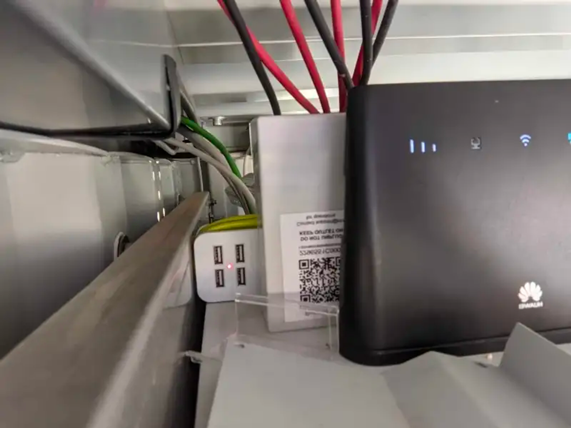 Figure 5: Left: An OffGridBox unit at a clinic where we installed one of the sensors. Right: A sensor installed inside the box unit. The sensor is plugged into the power extension cord behind the WiFi box. (Note: the red and black cables are NOT associated with the sensor).